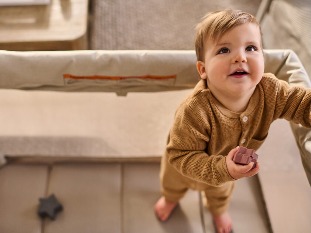 Child looks up while holding toy in the Remi. 