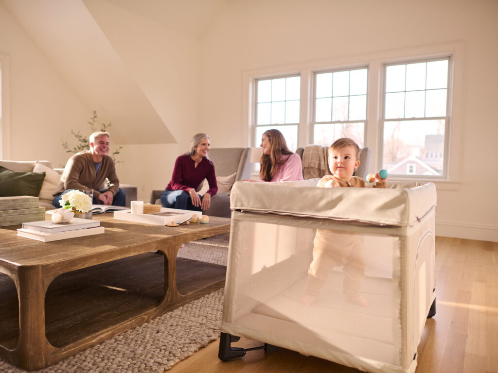 A child's family laughs and talks while a child occupies themselves in the Remi playard. 