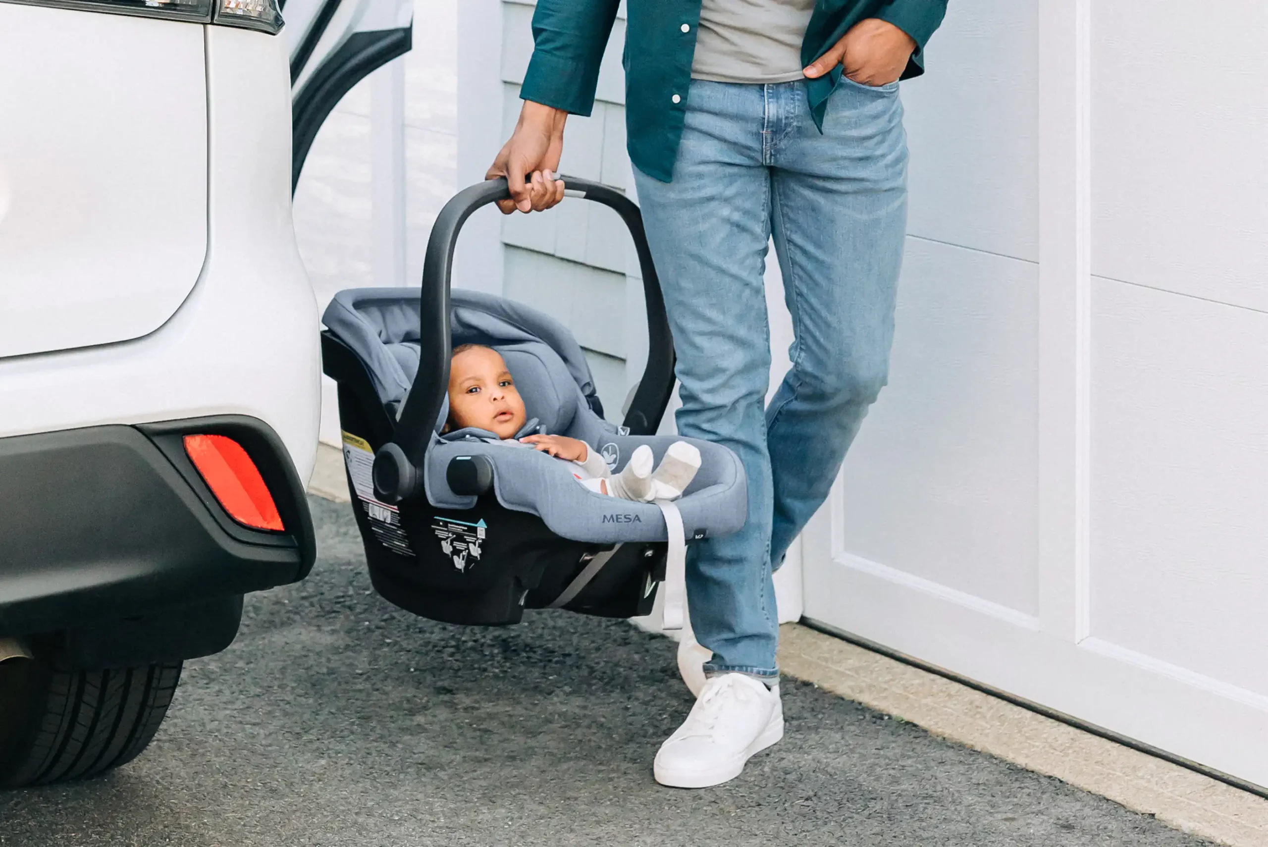 Parent walking away from car with infant in Mesa V2 infant car seat