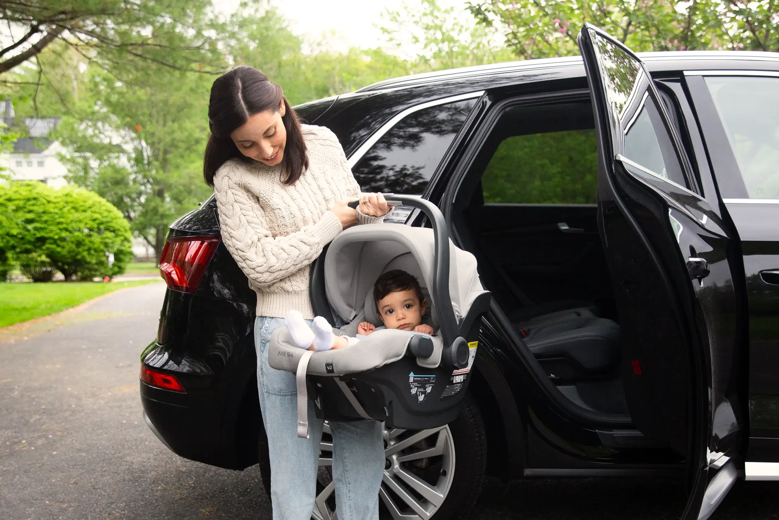 Mom smiling while disembarking from car with baby in Mesa V2 infant car seat