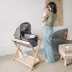 Parent holding child next to Bassinet resting in Bassinet Stand