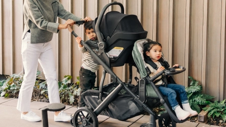 Parent pushes three children in Gwen Vista with forward facing RumbleSeat V2+ in Gwen fashion (lower), parent facing Mesa in Jake (upper), and PiggyBack