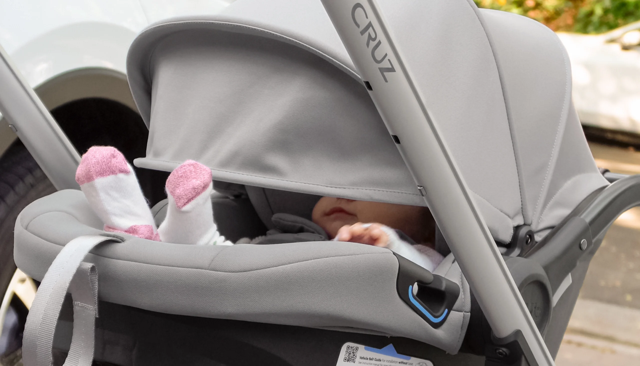 A child is shielded from the sun by the Aria's extra large canopy and pop-out sunshade, and stays cool with the seat's back panel ventilation while they stroll attached directly to a Cruz stroller