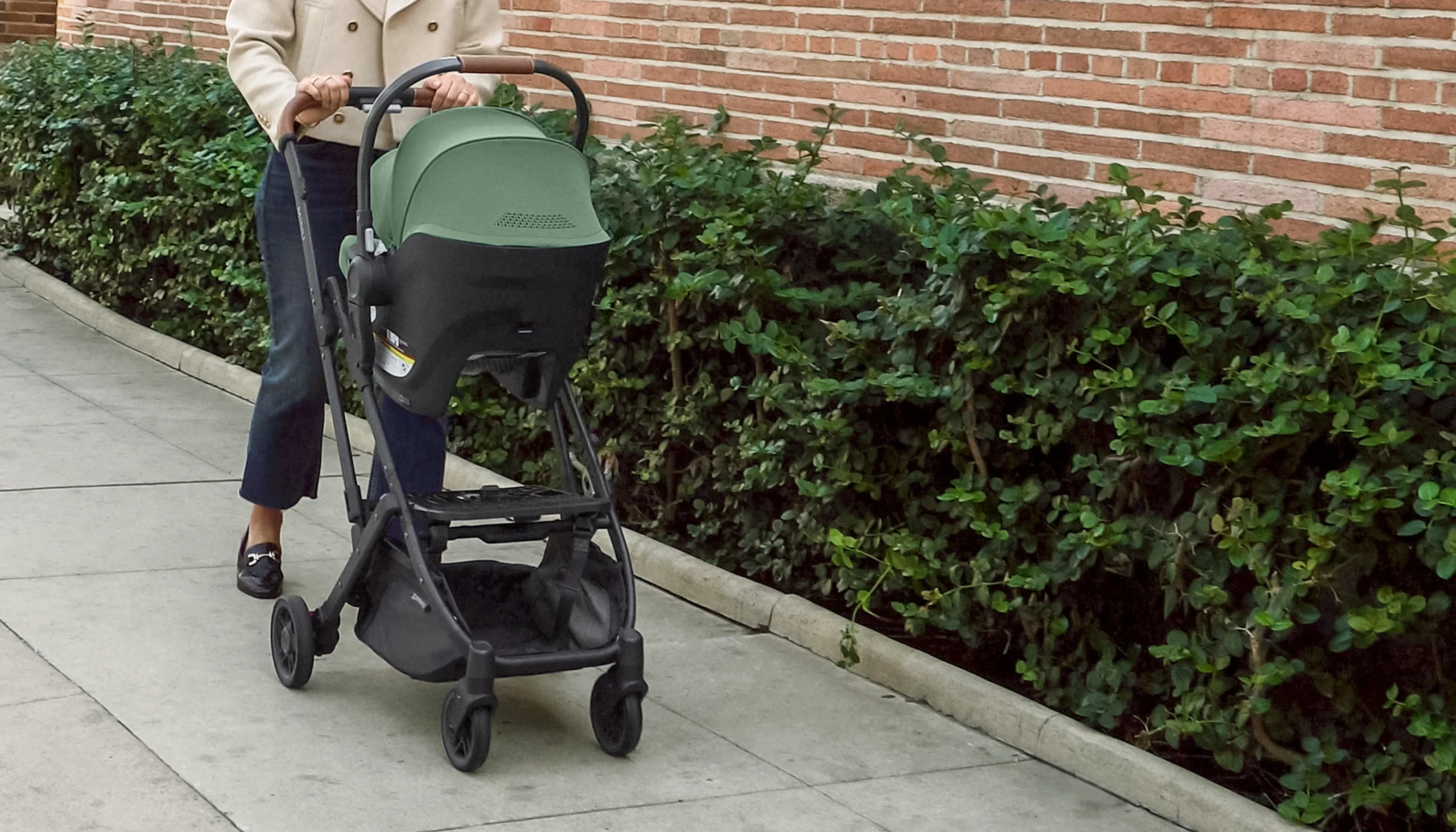 Parent pushing Minu V2 stroller with Aria infant car seat attached with the use of adapters