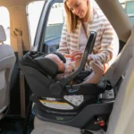 A woman smiles at her child safeley installed in the Aria car seat with its Anti-Rebound+ Panel for increased safety in collisions and greater head containment to improve side impact protection