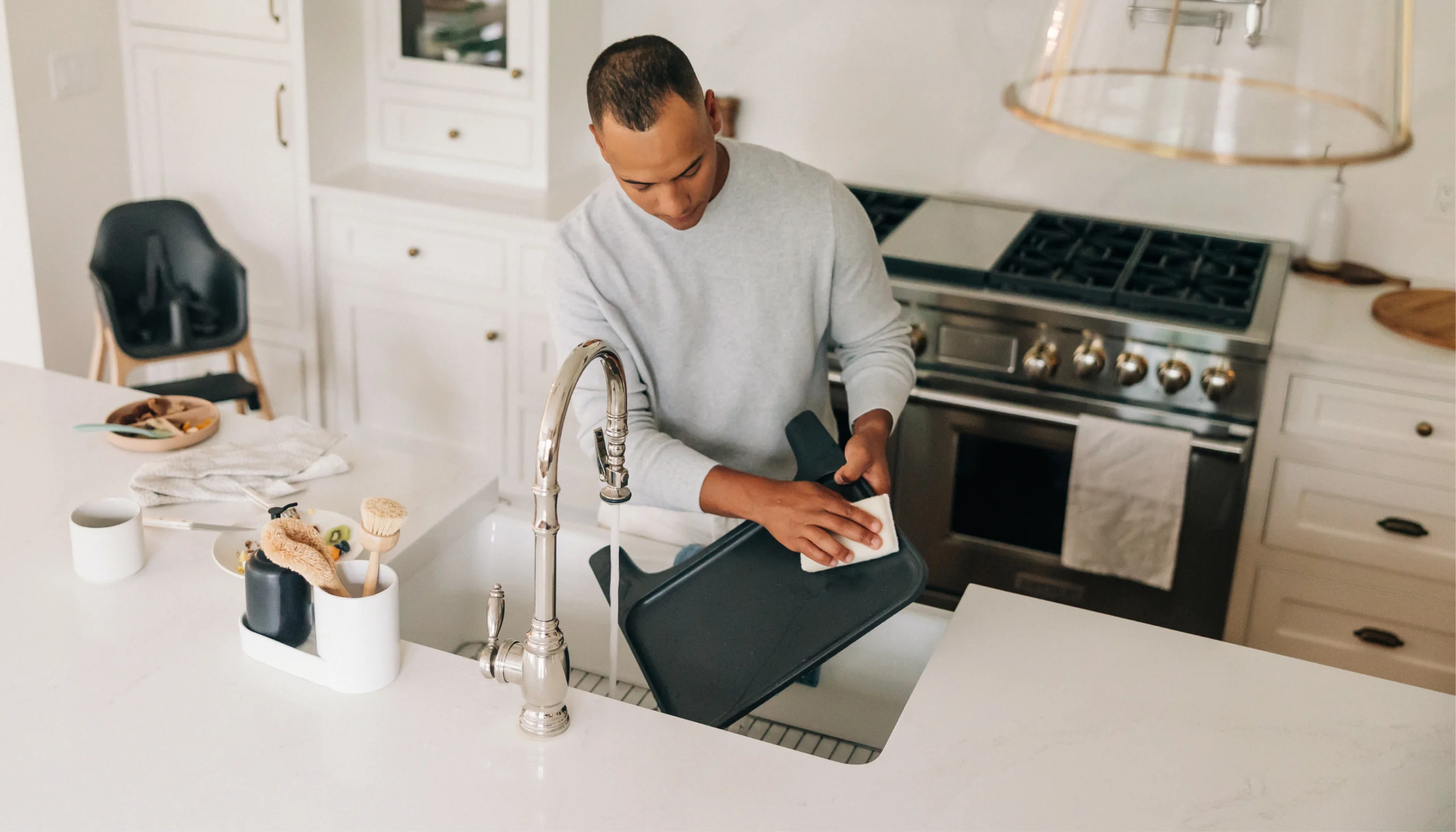 A man easily cleans and wipes down the removable Ciro High Chair tray, which is also dishwasher-safe