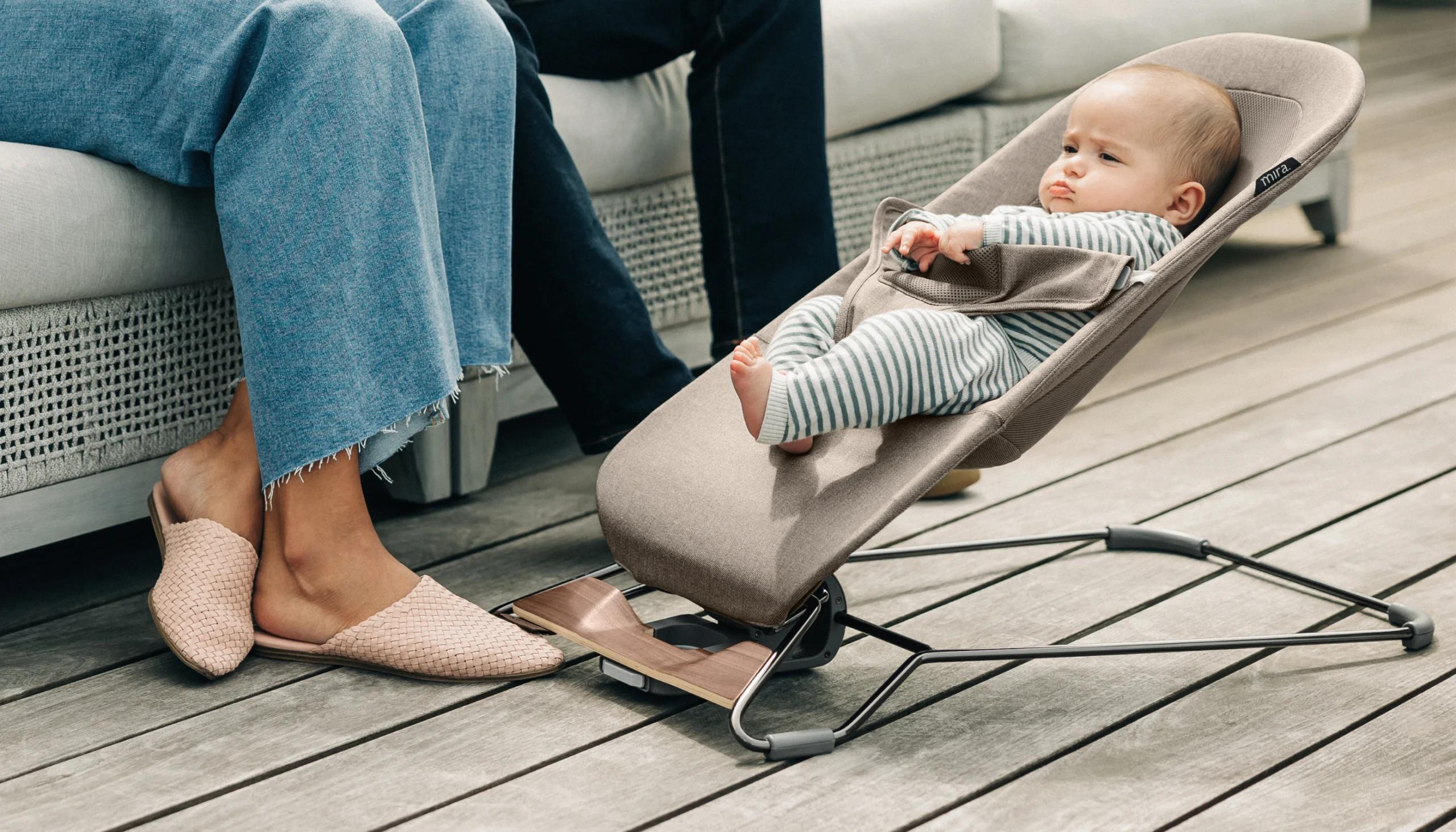 Baby comfortably relaxing in the Mira bouncer next to caretakers