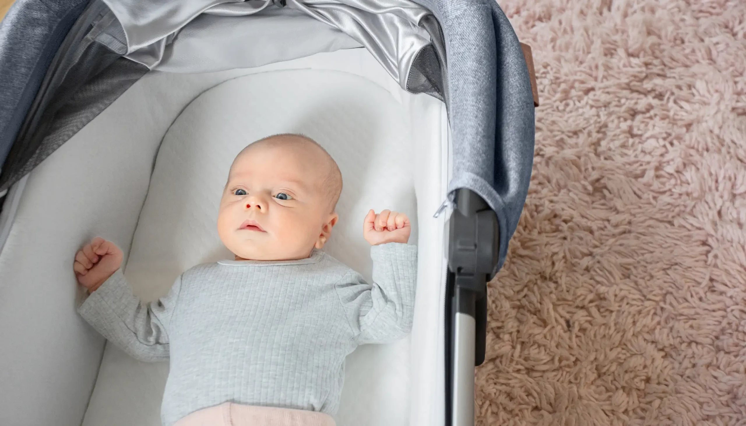 Child laying in Greyson Bassinet with White Mattress Cover for Bassinet