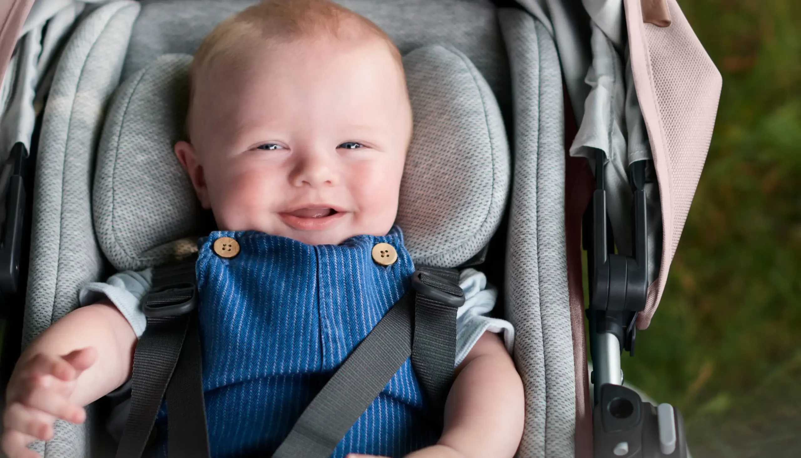 Smiling baby safely secured into Vista/Cruz Toddler Seat with use of Infant SnugSeat