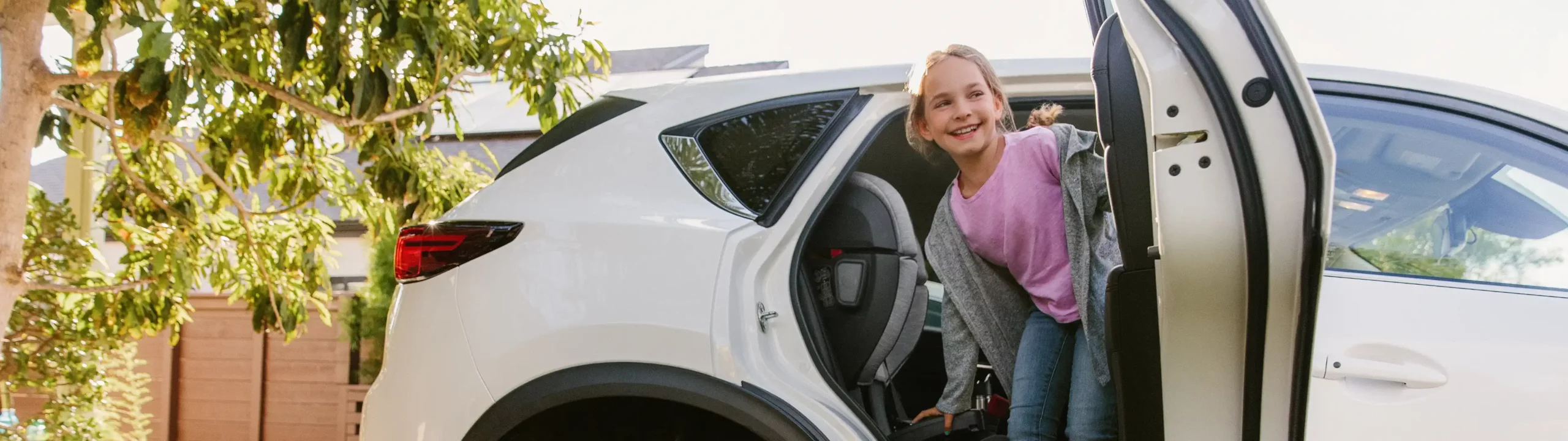 Child smiling as she disembarks from car with Alta car seat properly installed