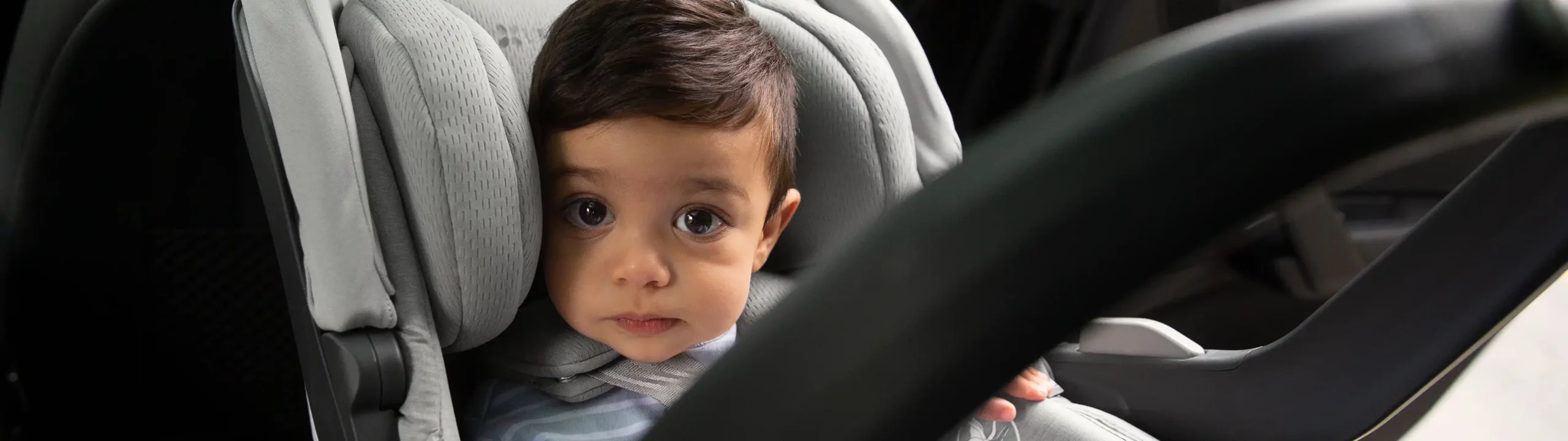 Young infant looking up while securely buckled into infant car seat