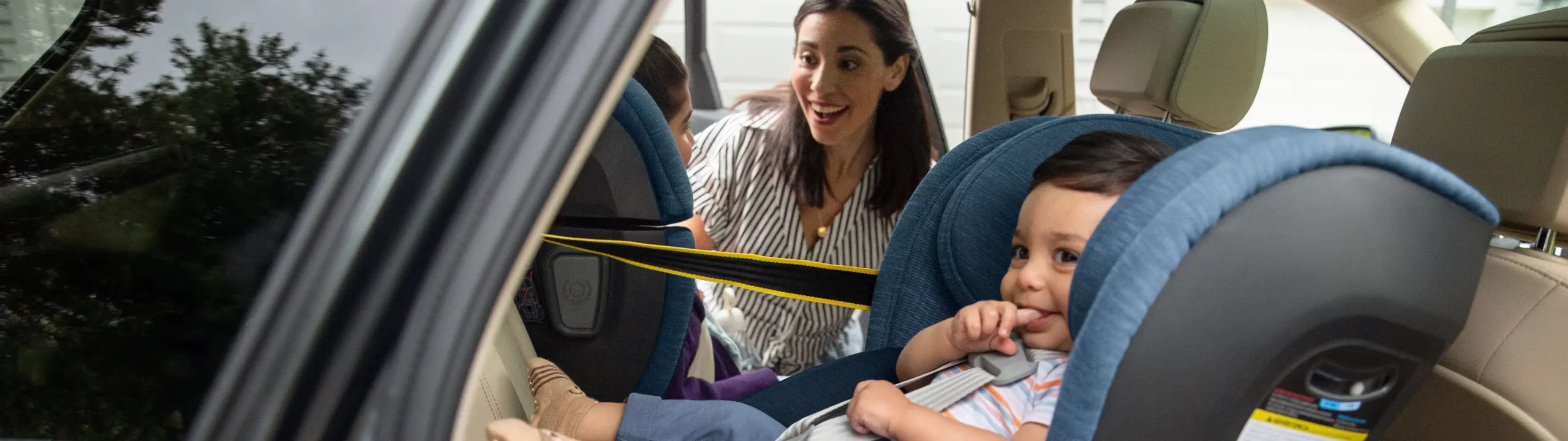 Mom smiles at her two children in the car, who are comfortably strapped into the Knox and Alta V2 carseats.