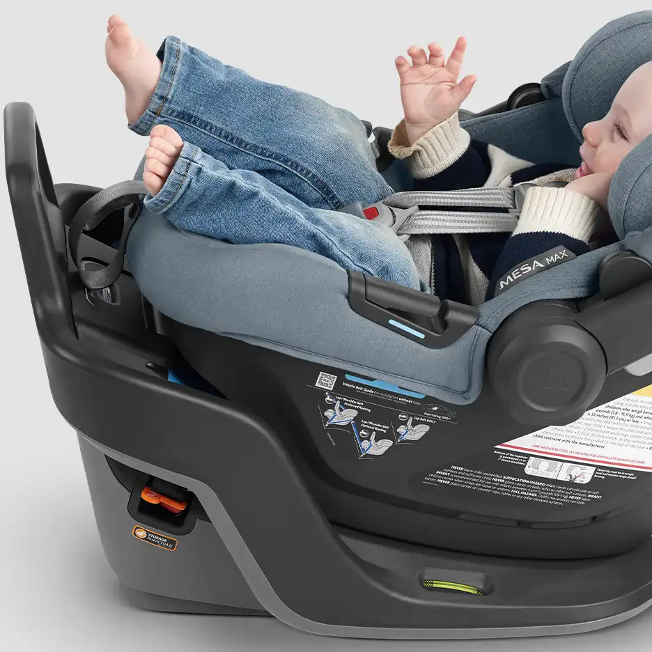 Closeup of infant in car seat with proper positioning of the crotch buckle. The crotch buckle is flush against the child’s lower body