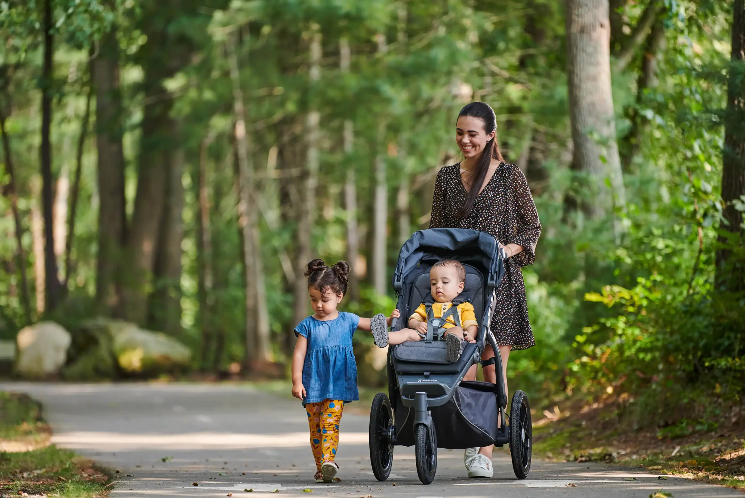 A smiling woman strolls with her Ridge, knowing she has the option for her child to sit up and sightsee or use the deep and comfortable seat with a webbing recline to snooze while jogging